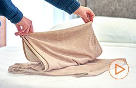 A woman holding up the Encircle before installing it on a hotel bed | watch instructional video