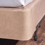 Encircle™ box spring cover in sand installed on a hotel bed