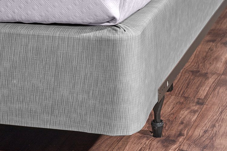 Encircle™ box spring cover in magnesium installed on a hotel bed