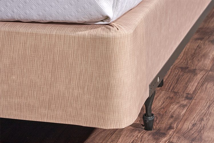 Encircle™ box spring cover in sand installed on a hotel bed