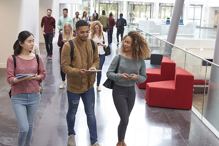 Image of students walking through a campus building with lounge area seen behind them.