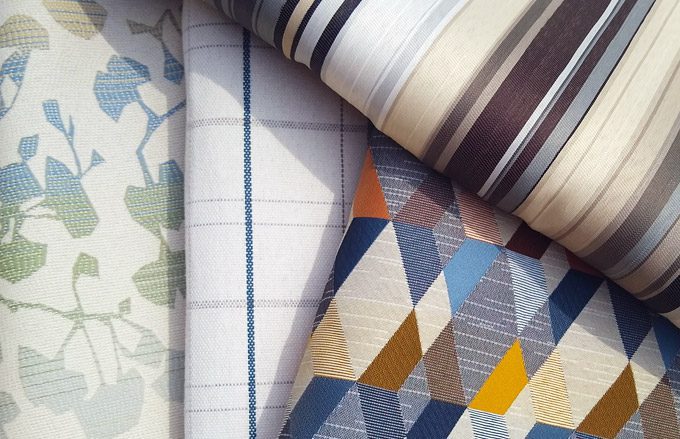 A variety of fabric swatches in several patterns and and stripes are stacked to show depth.
