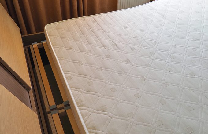 unmade mattress placed on bed frame in hotel room