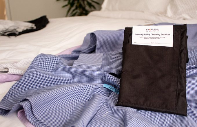 VersaValet laying upon a dry cleaned shirt placed on a white hotel room bed.
