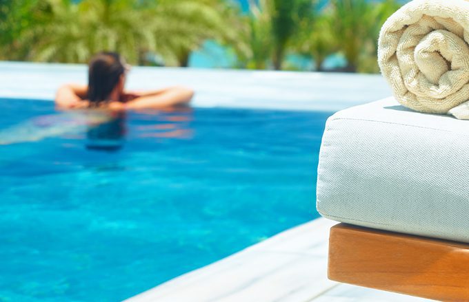 Hotel guest relaxing with rolled pool towel nearby