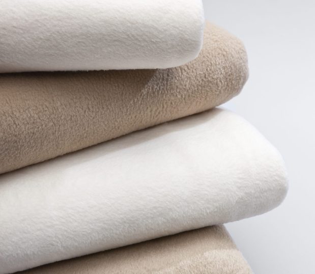 Stack of the Snow Storm blankets in ivory and tan. These are 100% polyester blankets.