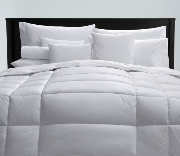 Image of a fluffy comforter on a bed with an assortment of white pillows.