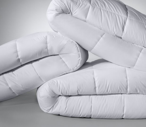 This is an image of three folded Elevations hotel comforters stacked artistically.