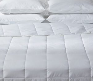 Photo of the Innerloft, all seasons duvet insert. Shown on a bed with white pillows