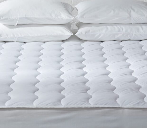 Image is of a Comfort Cloud a plush mattress pad shown on a bed with pillows.