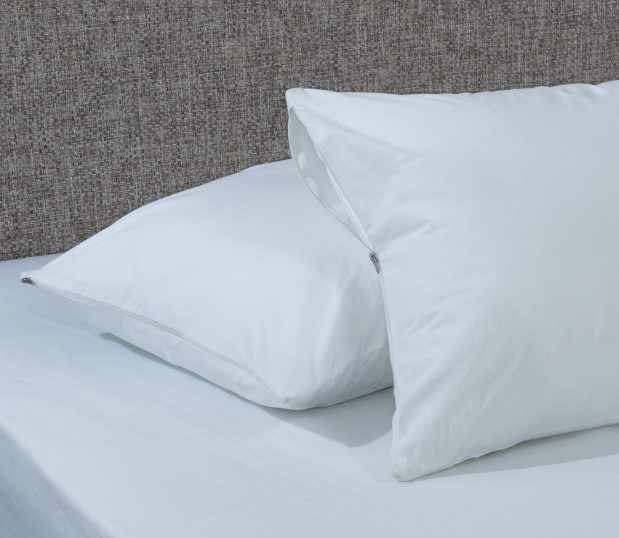 Two pilows with 100% cotton pillow covers are laying on a bed. An allergy pillow cover is a breathable barrier that protects against dust mites and allergens at an affordable price.