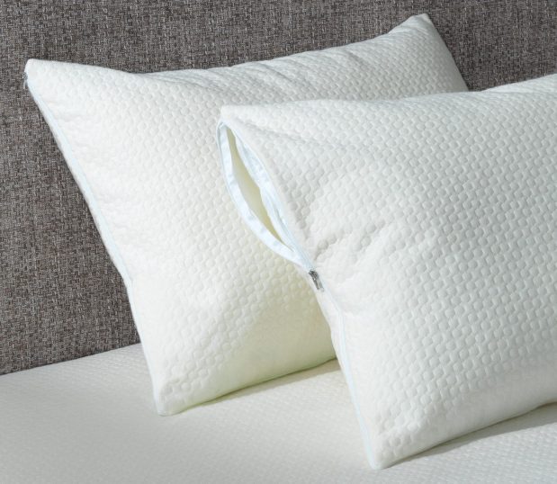 image of two pillows with waterproof pillow covers leaning against a headboard on a bed.