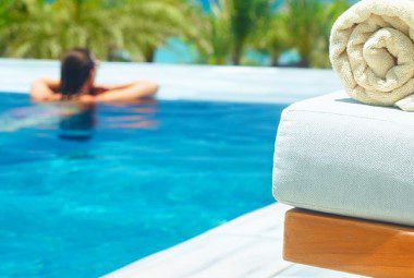 A rolled up pool towel on a lounge chair next to a hotel pool.