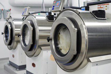 A row of industrial washing machines cleaning hotel linens