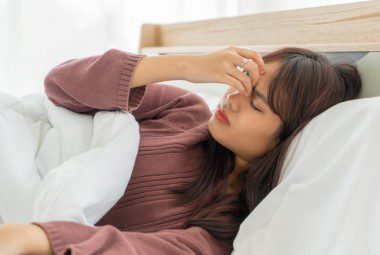 Woman with allergies lying in a hotel bed.