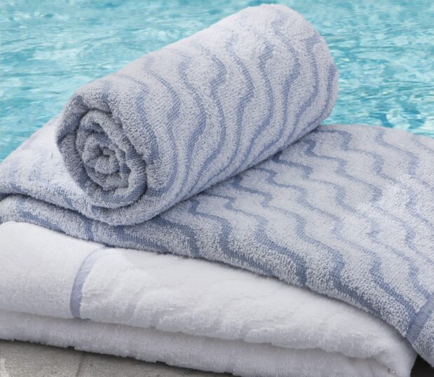 a collection image of our EuroSpa blue terry beside a hotel pool.
