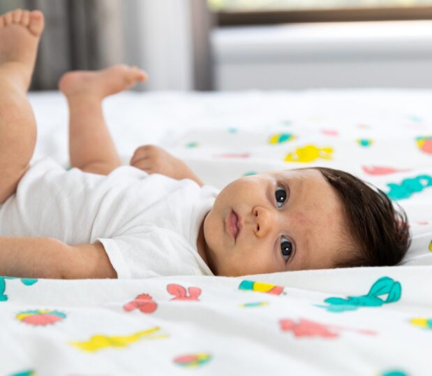 Cute dark haired baby laying on our Bunnyland baby blanket..