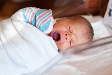 Our Striped Baby Blankets feature a cotton-rich fabric made to provide all the softness and warmth required for life’s first moments. Featuring classic pink & blue stripes. Shown here: an infant wrapped in the striped baby blanket.