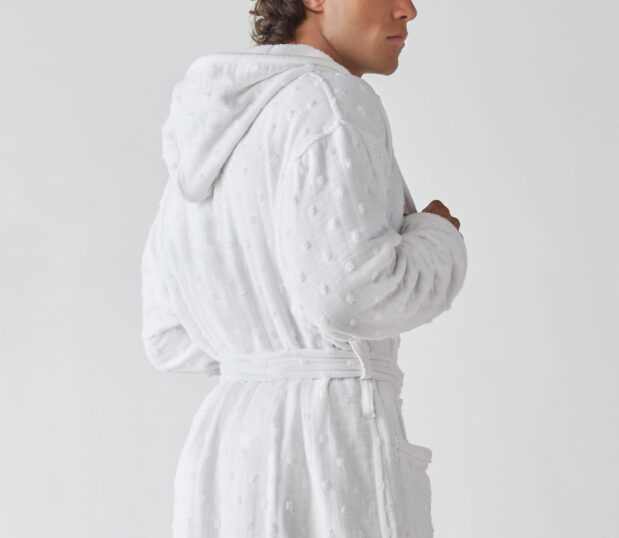 The Billy Bathrobe is a white cotton bathrobe and has a hood, pockets and a woven polka-dot pattern.