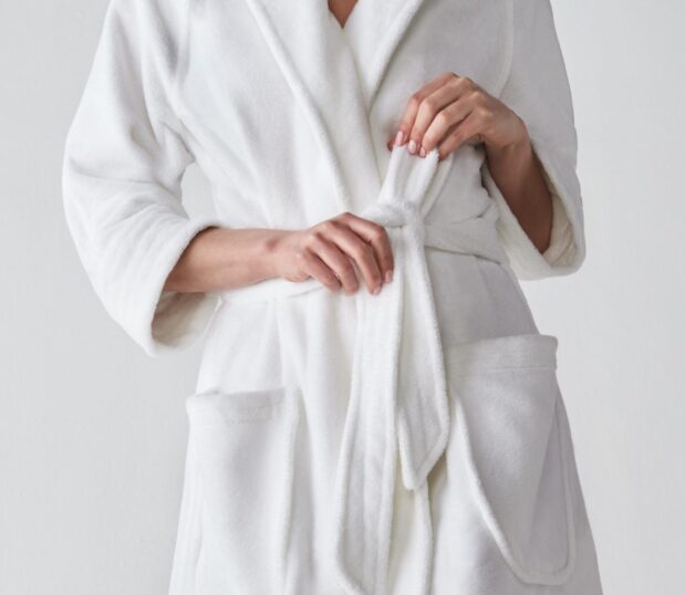 Detail of a model's hands tying the waist of the plush, white, Nikki Bathrobe.