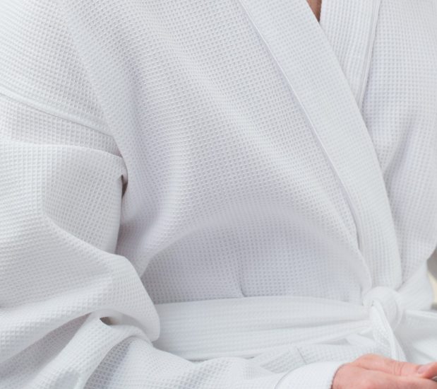 Detail of a model wearing the white, waffle spa robe.