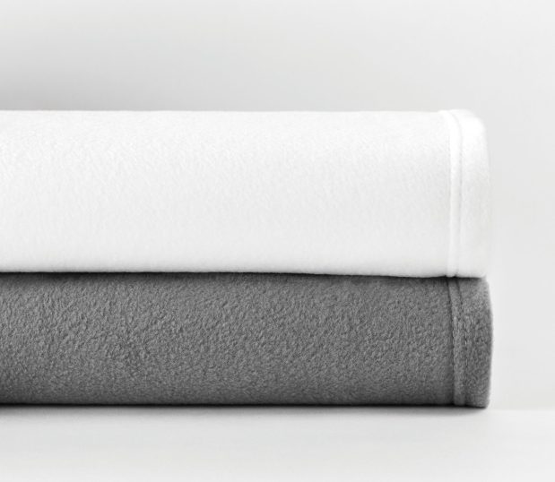 Shown stacked are the Express by Standard Textile fleece blankets in White and Grey.
