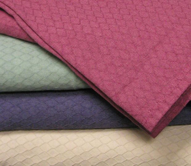 A stack of Gemstone healthcare bedspreads. This bedspread has a diamond pattern.