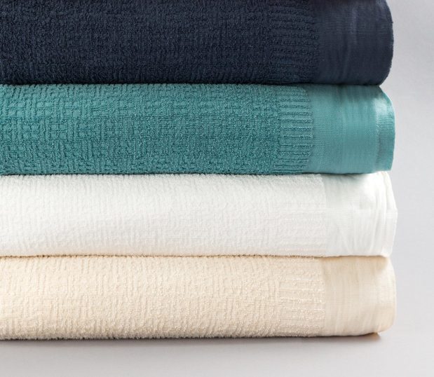 A stack of Insulite® Blankets in all four colorways Cobalt, Natural, Teal, & White.
