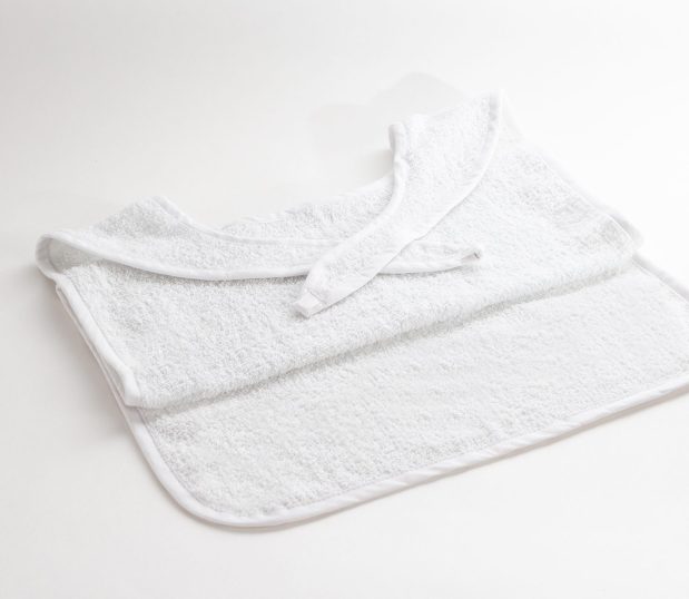 This white adult bib is a Terry Self-Closure Clothing Protector. It conveniently ties at the neck for easy fit.