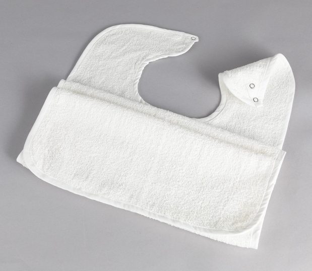 This white adult bib is a Terry Snap Clothing Protector. These washable adult bibs help residents of senior living facilities keep their clothing clean while they eat.