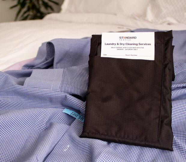 Made from 100% recycled polyester, the VersaValet™ features an antimicrobial finish for added protection and peace of mind. Image shows the VersaValet Hybrid Garment & Laundry Bag folded on a piece of dirty laundry.