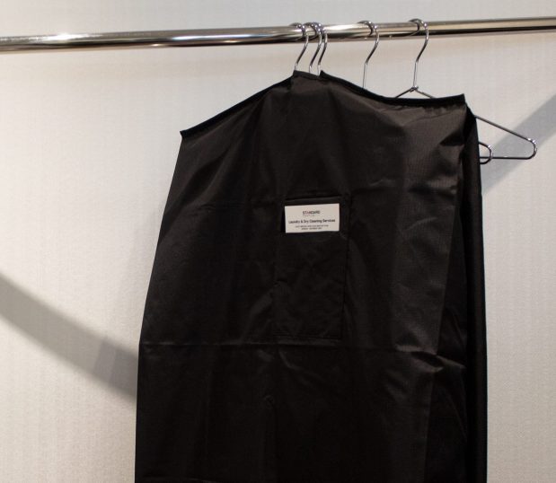 Made from 100% recycled polyester, the VersaValet™ features an antimicrobial finish for added protection and peace of mind. Image shows the VersaValet Hybrid Garment & Laundry Bag hanging in a closet setting with clothes inside.