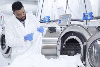 Laundry attendant inspecting sheets for damage.