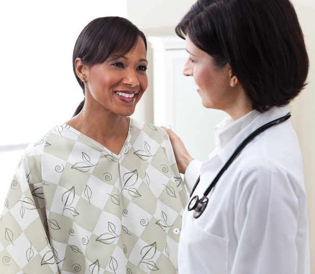 Patient wearing our E*Star® Double Lapover Patient Gown talking with her doctor. These patient gowns are a double lapover V-neck design that features fast drying 100% polyester.