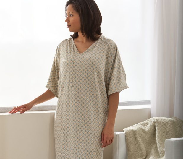 Female patient wearing the Healing Spaces® Patient Gown. This hospital gown has a double lapover V-neck design made soft cotton/polyester knit. Options include raglan sleeves, I.V. sleeves, and telemetry pocket.