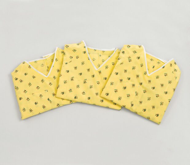 Three Risk Identity Patient Gowns folded and laying in a semi-circle. The pattern for this hospital gown s Kaleidoscope Yellow color.