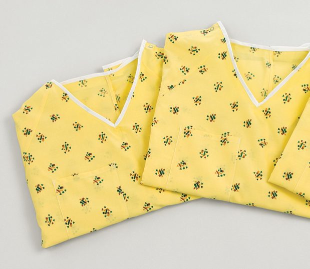 Detail of the pattern the Risk Identity Patient Gown. Kaleidoscope Yellow has a yellow background with clusters of squares, triangles and rectangles in bright colors.