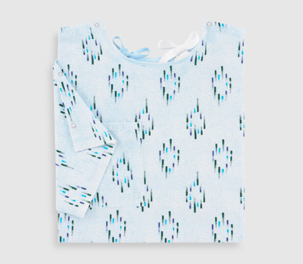 Folded multipurpose patient gown in Champagne Blue. This hospital gown features a Telemetry Pocket and IV sleeves.