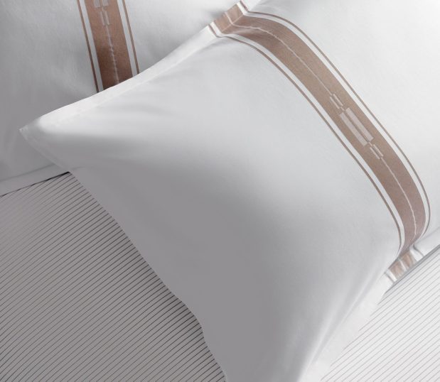 Detail image of Concerto Pillow Sham. It's a white sheet with a beige stripe pattern that is designed to feel like music.