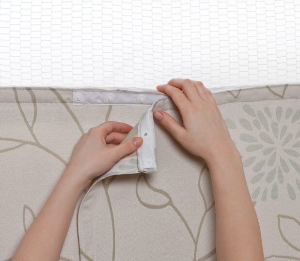 Hands snapping on the Perfect Panel Privacy Curtain showing how easy they are to replace. Consider custom fabrics for your cubicle curtains.