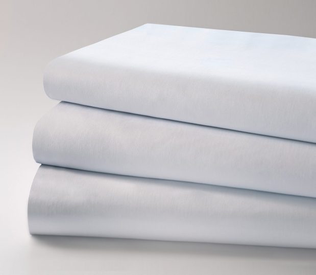 Standard Classic Muslin Woven Sheeting for hospitals and health systems. Available in flat sheets or pillowcases. Shown folded in a stack.
