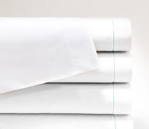 T-130 Woven Sheeting for hospitals and health systems for healthcare bedding. Available in flat sheets, contour sheets, drawsheets, or pillowcases. Shown in a folded stack in the color Bleached White.