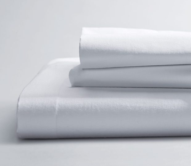T-180 Woven Sheeting for hospitals and health systems hospital bedding. Available in flat sheets, contour sheets, drawsheets, or pillowcases. Shown in a folded stack in the color Bleached White.