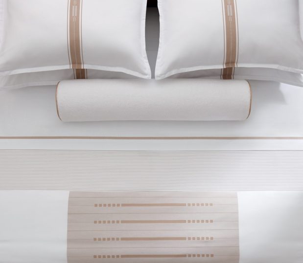 Concerto Sheeting shown from an over-head view on bed with a bolster and pillow shams.