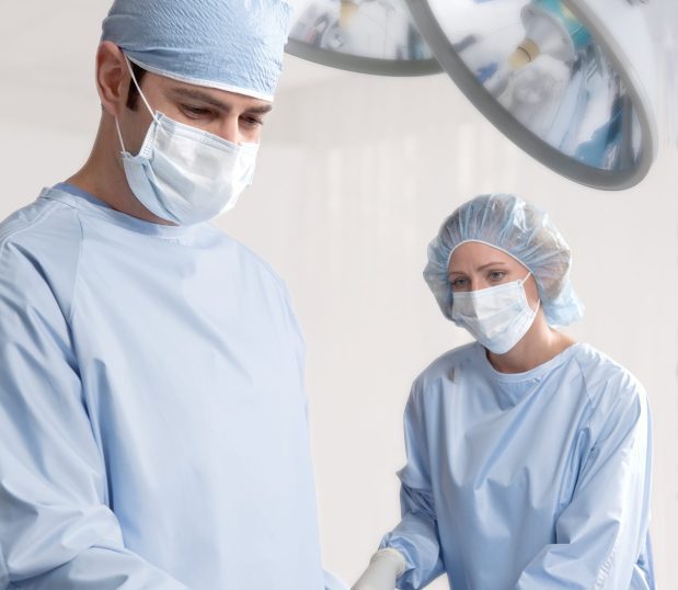 Image of two doctors in an operating room wearing our ComPel® MLR Surgical Gown. These reusable surgical gowns meet AAMI PB70 Level 3 barrier standards.