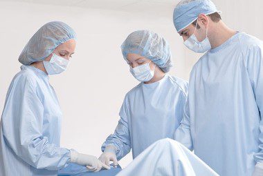 A team of surgical nurses observe a patient.