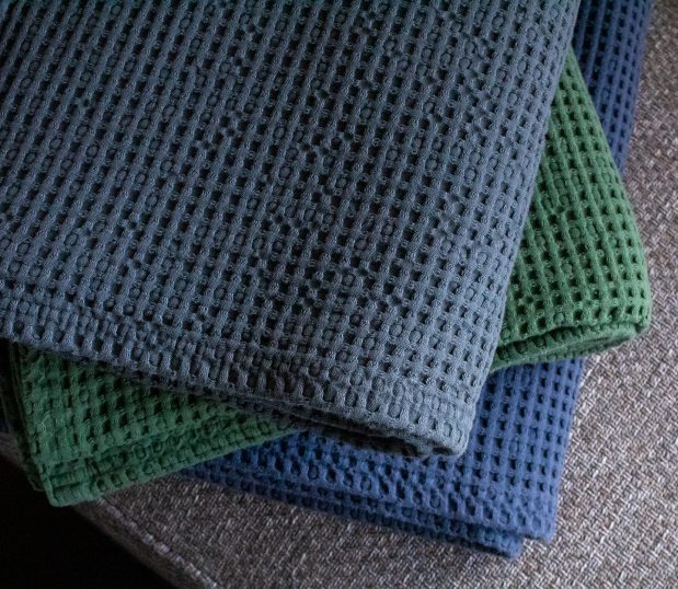 Stack of three Honeycomb Waffle Throw blankets in Charcoal, Denium and Evergreen.