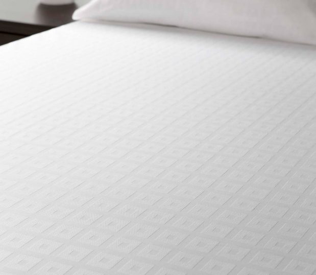 No duvet doesn’t have to mean no sophistication. This block-on-block decorative top cover adds elegance without the hassle of duvet inserts. Image shows a block on block top cover on a bed.