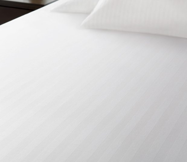Add a subtle touch of sophistication to your top of bed with this decorative stripe top sheet. Also available in sheeting and pillowcases for an impressive bedding ensemble. Shown Here: a ComforTwill top cover on a bed.