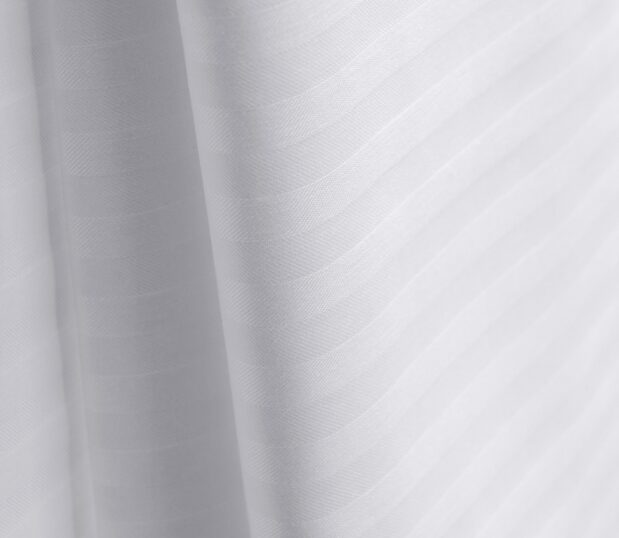 Add a subtle touch of sophistication to your top of bed with this decorative stripe top sheet. Image shows a detail shot of a ComforTwill stripe top cover.